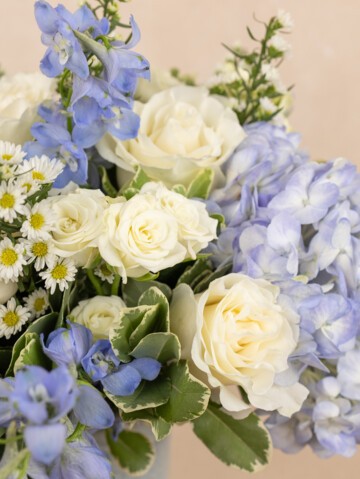 Close-up of Enora bouquet.  Mixed coastal bouquet featuring blue hydrangeas, white roses & more