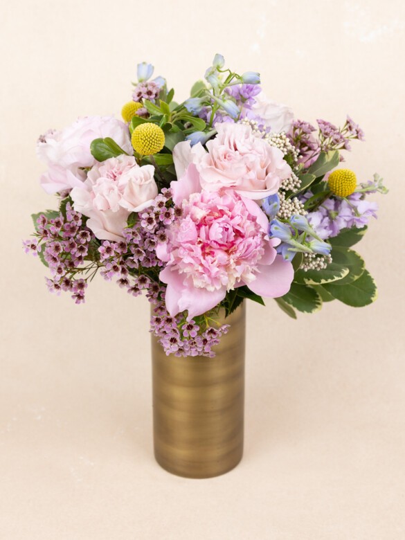 Elegant 23-stem bouquet with pink roses, peonies, lavender blooms, and yellow craspedia, arranged in a modern bronze vase with wild texture.