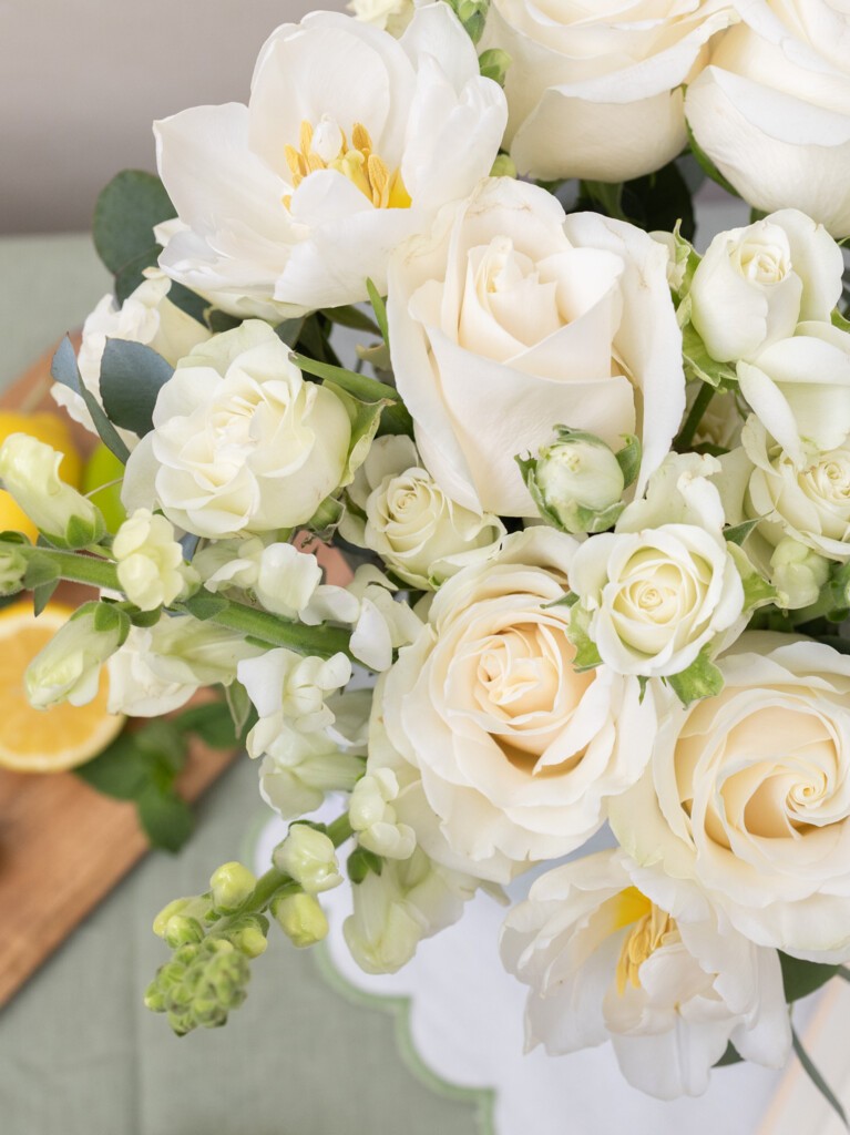 Close-up of Paulette 26-stem bouquet with white tulips, roses, snapdragons, and spray roses, emphasizing bloom texture and fresh seasonal quality.