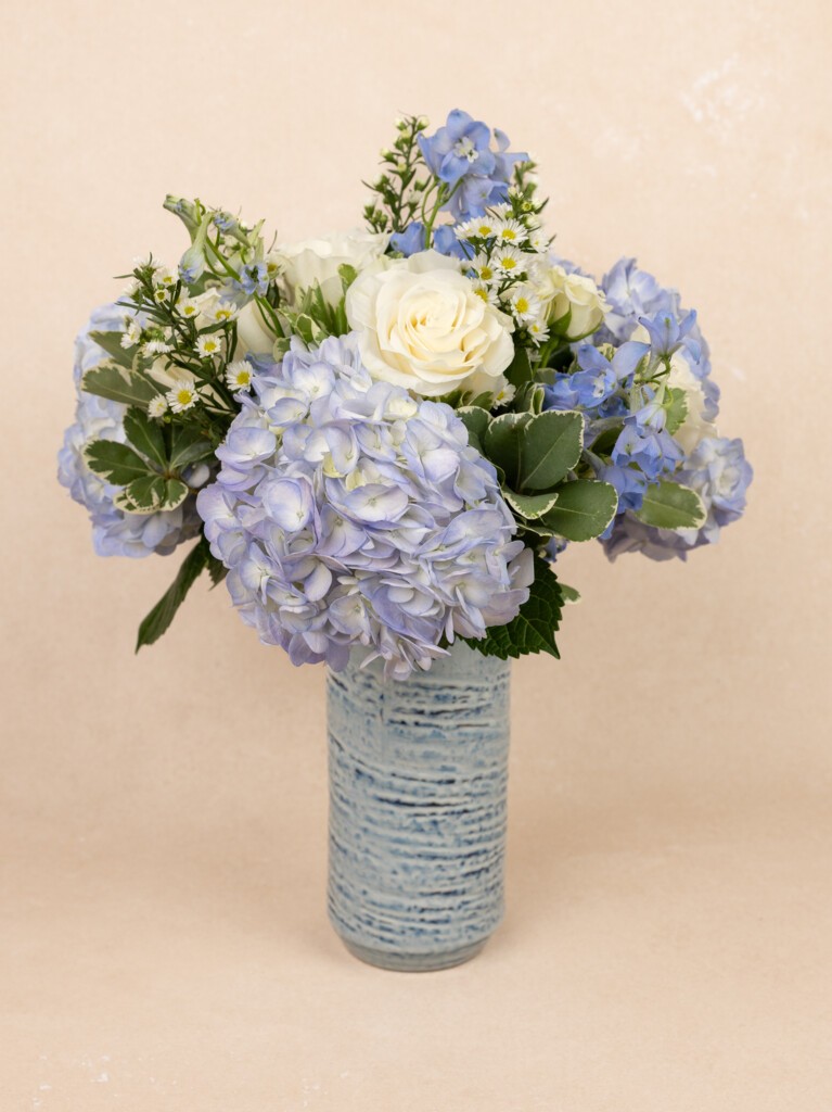 Enora bouquet in blue ceramic vase.  Mixed coastal bouquet featuring blue hydrangeas